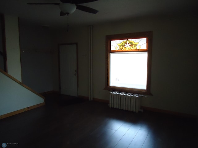 spare room featuring ceiling fan, radiator heating unit, and wood-type flooring