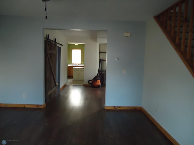 spare room featuring a barn door and dark wood-type flooring