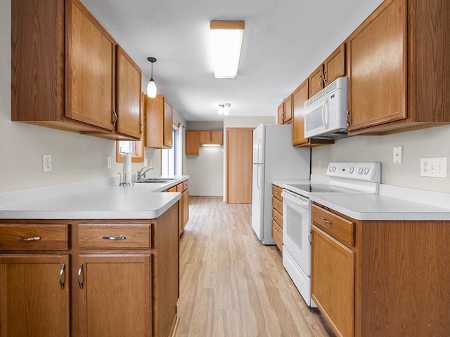 kitchen with light hardwood / wood-style floors, white appliances, hanging light fixtures, and sink