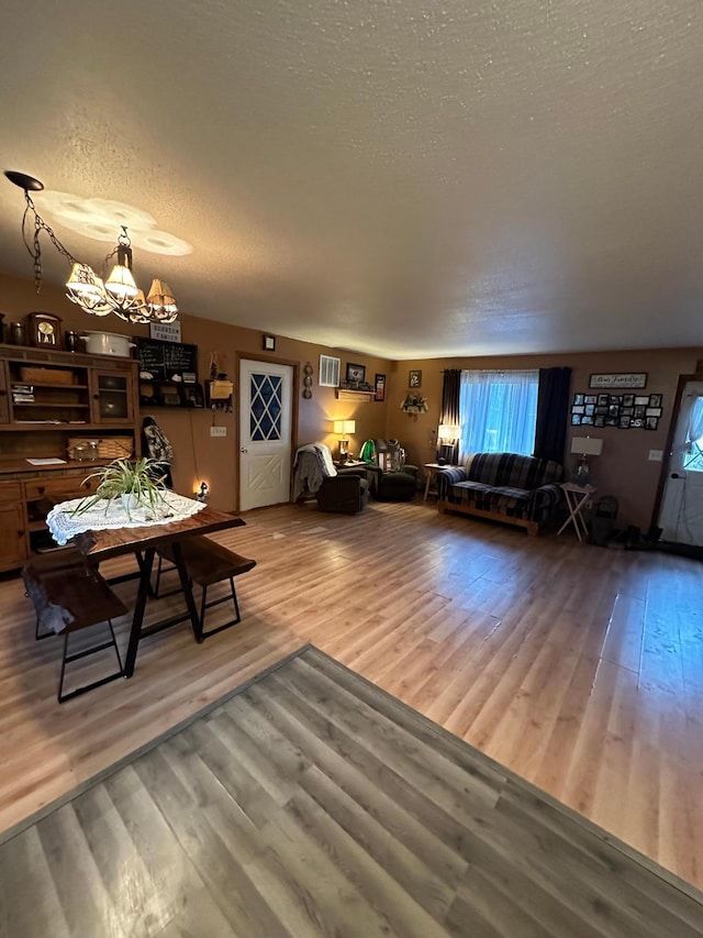 living room featuring a textured ceiling, hardwood / wood-style flooring, and a notable chandelier