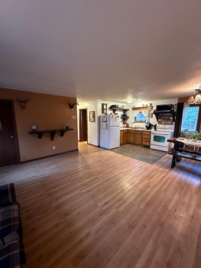 unfurnished living room featuring a chandelier and light hardwood / wood-style flooring