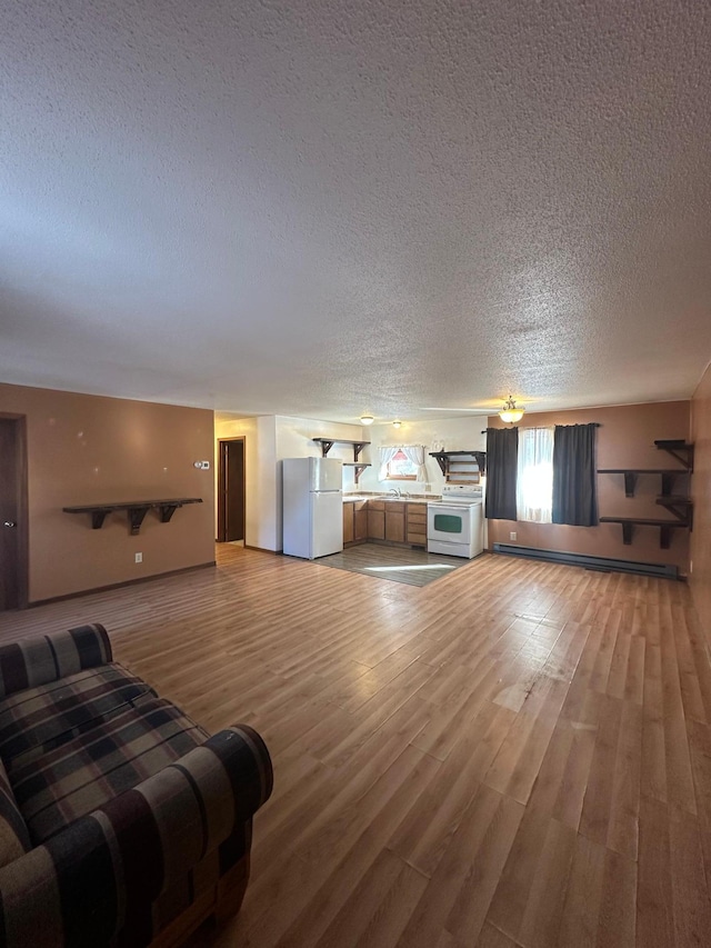 living room featuring a baseboard radiator, a textured ceiling, and light wood-style flooring