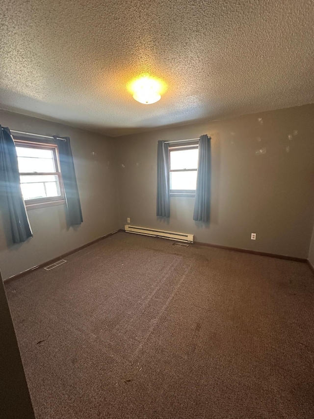 carpeted empty room featuring a baseboard radiator, baseboards, a healthy amount of sunlight, and visible vents