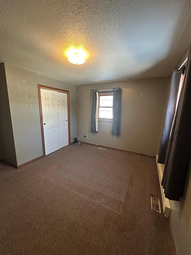 interior space featuring carpet, baseboards, visible vents, a closet, and a textured ceiling