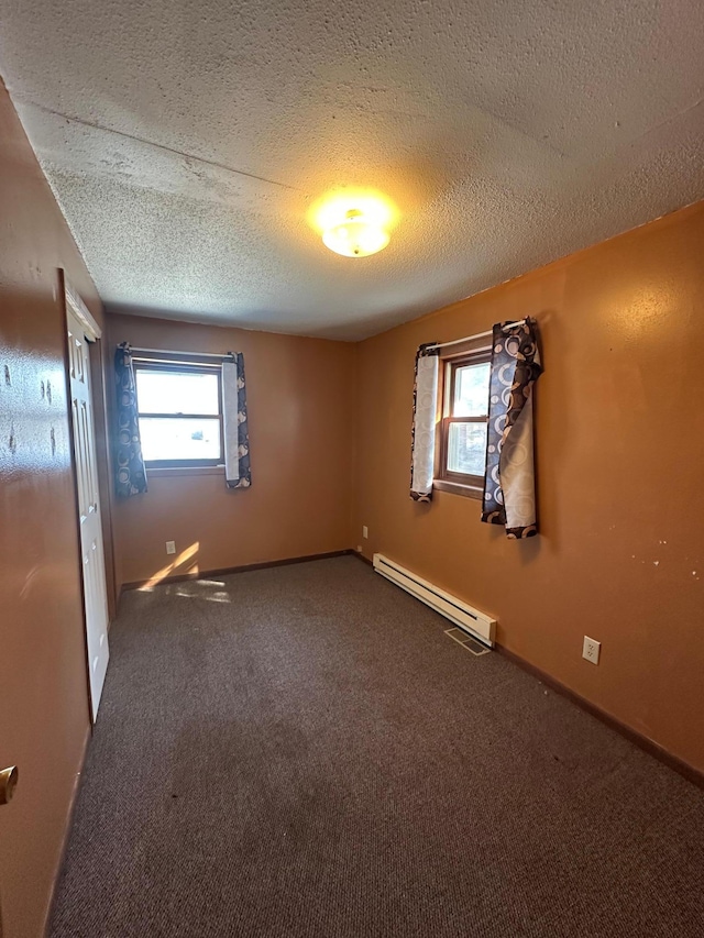 unfurnished room with carpet flooring, a textured ceiling, baseboards, and a baseboard radiator