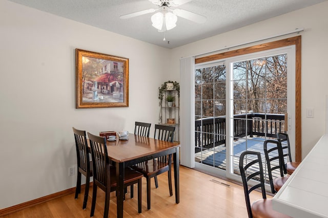 dining area featuring light wood-type flooring, ceiling fan, and a textured ceiling