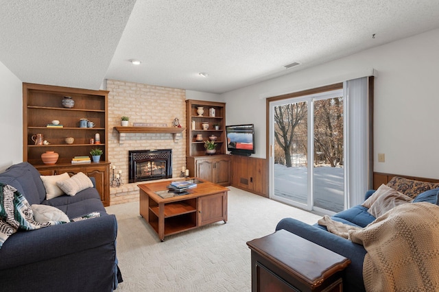 carpeted living room with wooden walls, a textured ceiling, and a fireplace