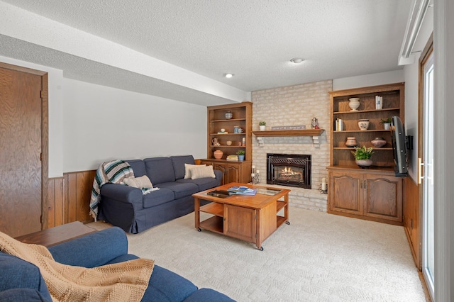 living room with wood walls, light carpet, a textured ceiling, and a fireplace