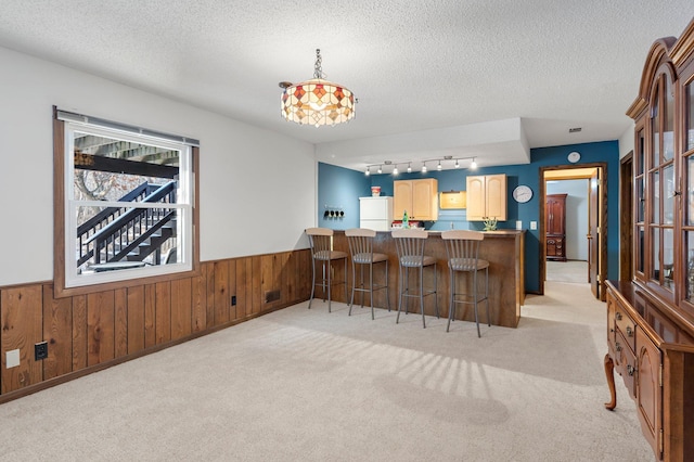 kitchen featuring kitchen peninsula, a textured ceiling, wooden walls, light colored carpet, and white refrigerator