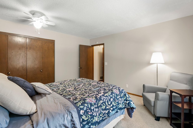 bedroom featuring a textured ceiling, ceiling fan, a closet, and light carpet