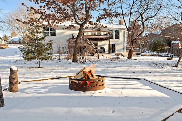 snow covered property with an outdoor fire pit and a wooden deck