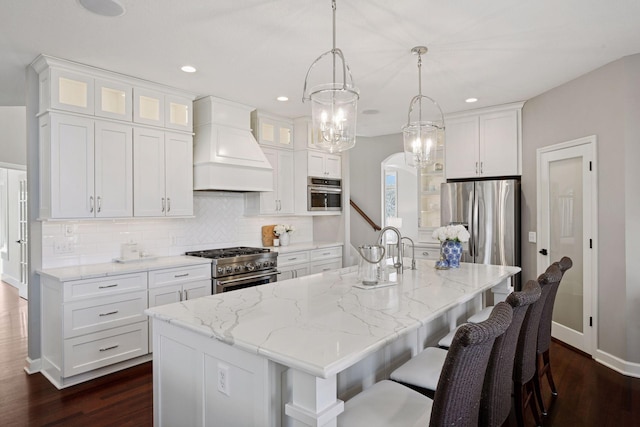 kitchen with decorative backsplash, appliances with stainless steel finishes, white cabinets, and custom range hood