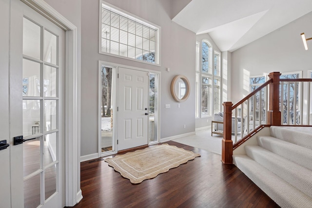 foyer entrance with stairway, a healthy amount of sunlight, baseboards, and wood finished floors