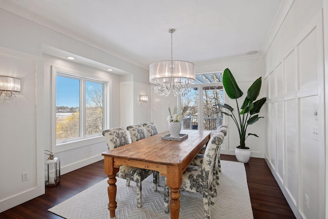 dining area with dark wood finished floors, a notable chandelier, baseboards, and ornamental molding