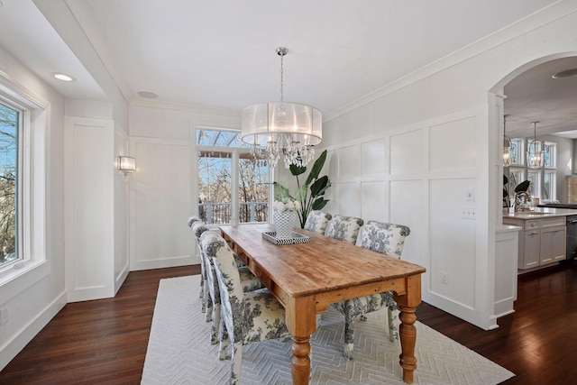 dining room with a decorative wall, plenty of natural light, an inviting chandelier, and dark wood-style flooring