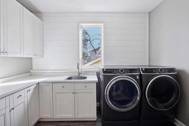 laundry room with cabinet space, independent washer and dryer, dark wood-style flooring, and a sink