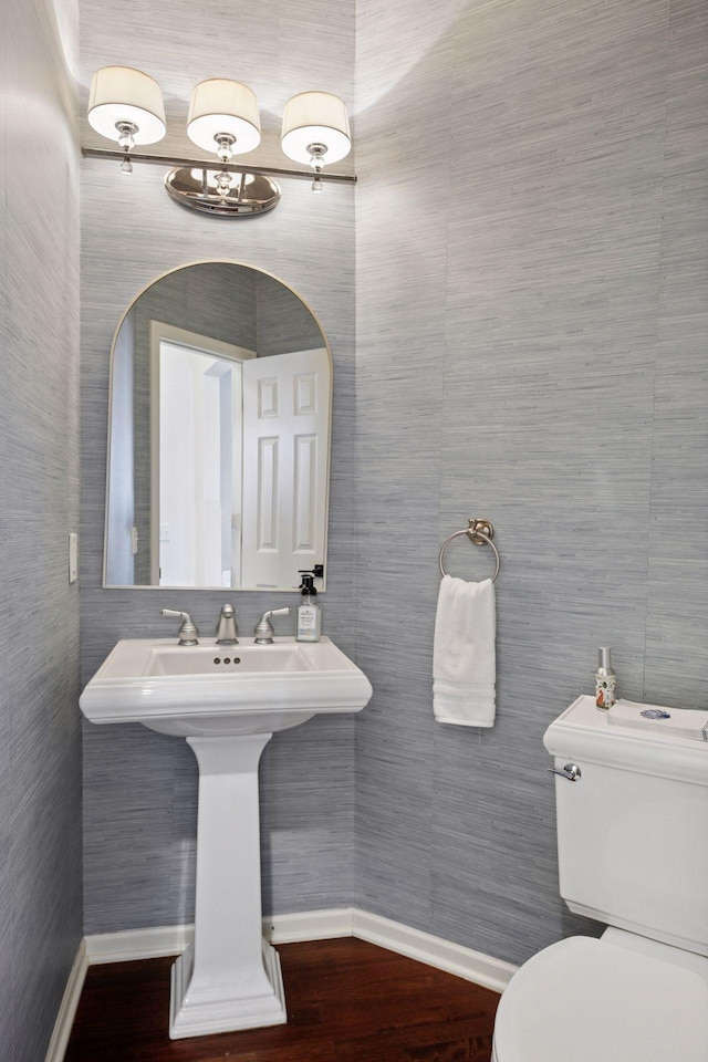 half bathroom featuring toilet, wood finished floors, and baseboards