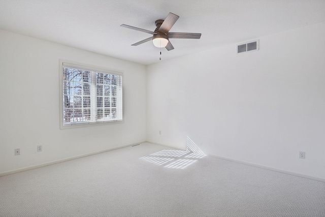 carpeted empty room featuring a ceiling fan, visible vents, and baseboards