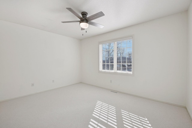 spare room with carpet flooring, visible vents, baseboards, and ceiling fan