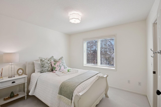 bedroom with light carpet, a textured ceiling, and baseboards