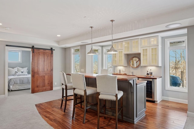 bar with wine cooler, plenty of natural light, baseboards, and a barn door