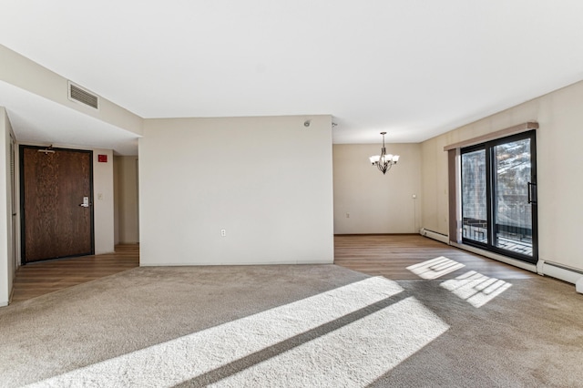 empty room featuring a baseboard heating unit, light carpet, and an inviting chandelier