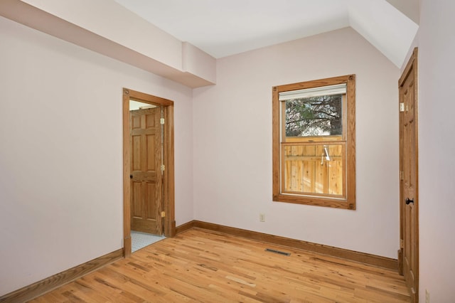 unfurnished room featuring vaulted ceiling and light hardwood / wood-style flooring