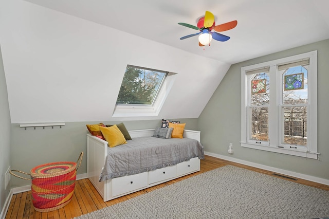 bedroom with wood-type flooring, lofted ceiling with skylight, and ceiling fan