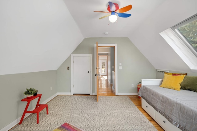 bedroom with multiple windows, vaulted ceiling with skylight, light hardwood / wood-style floors, and ceiling fan