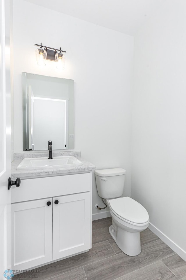 bathroom featuring toilet, vanity, and hardwood / wood-style flooring