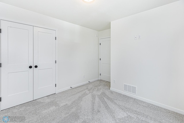 unfurnished bedroom with light colored carpet and a closet