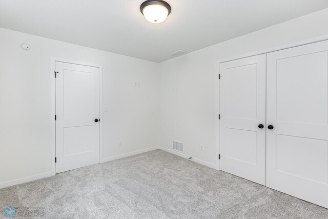 unfurnished bedroom with light colored carpet and a closet