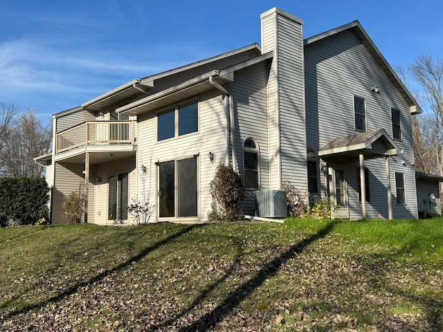 rear view of property featuring a lawn, cooling unit, and a balcony