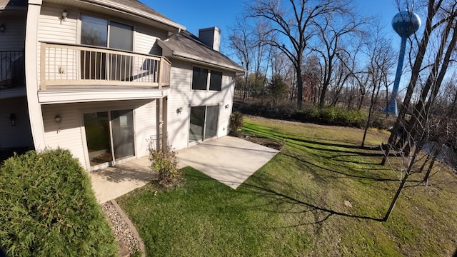 rear view of house featuring a yard, a balcony, and a patio area