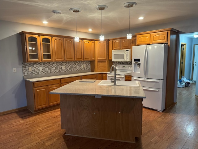 kitchen with sink, dark hardwood / wood-style flooring, white appliances, decorative backsplash, and a center island with sink