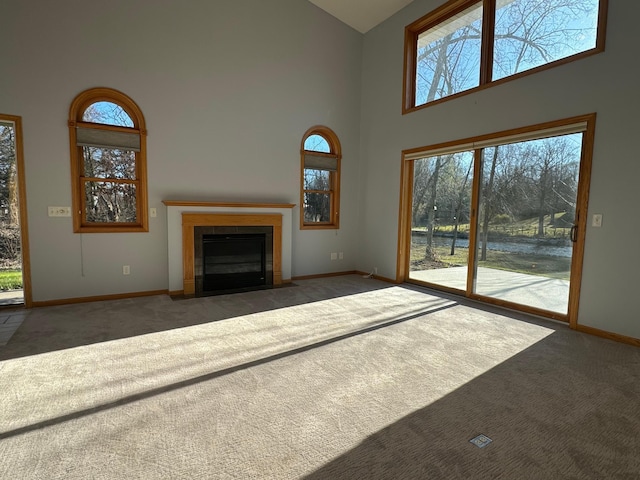 unfurnished living room with dark colored carpet, high vaulted ceiling, and a wealth of natural light