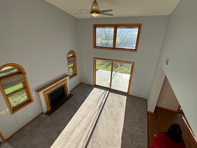 carpeted living room with a towering ceiling and ceiling fan