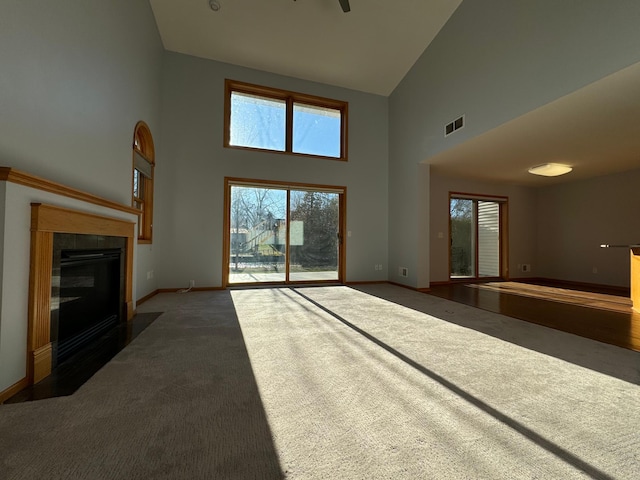 unfurnished living room featuring a towering ceiling and dark carpet