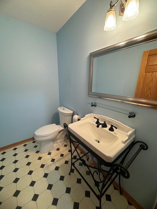 bathroom featuring a textured ceiling, toilet, and sink