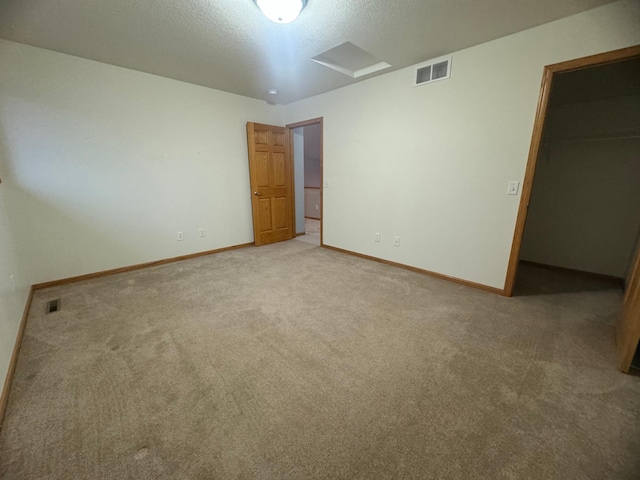 unfurnished bedroom with a textured ceiling, a spacious closet, carpet floors, and a closet