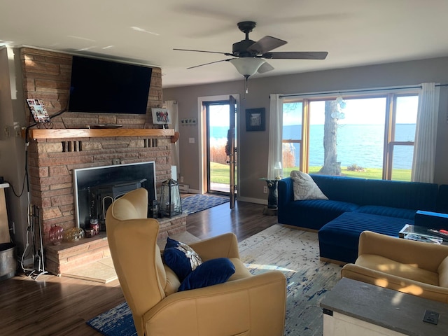 living room with ceiling fan, a water view, a fireplace, and light hardwood / wood-style flooring