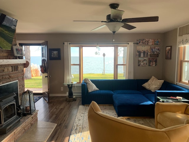 living room featuring a water view, a wood stove, dark hardwood / wood-style floors, and a healthy amount of sunlight