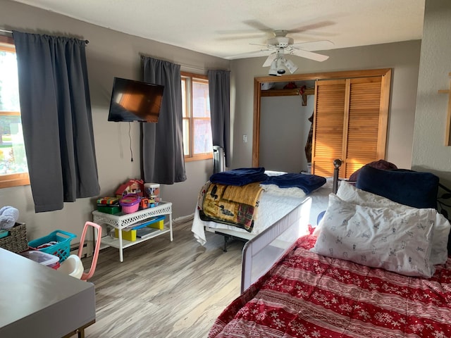 bedroom with ceiling fan, a closet, and light hardwood / wood-style flooring