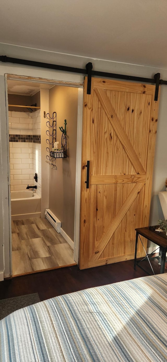 bedroom with a barn door, dark hardwood / wood-style flooring, connected bathroom, and a baseboard radiator