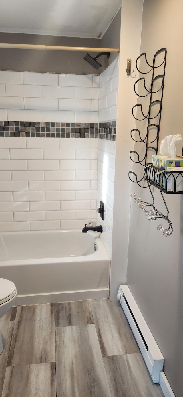 bathroom with toilet, hardwood / wood-style floors, a baseboard radiator, and tiled shower / bath