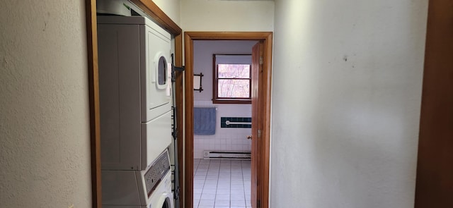 hall with light tile patterned floors, stacked washing maching and dryer, tile walls, and a baseboard heating unit