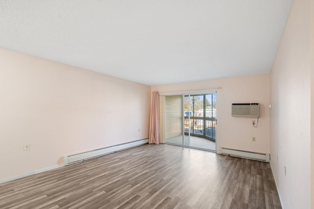 unfurnished room featuring a wall mounted air conditioner, hardwood / wood-style floors, and baseboard heating