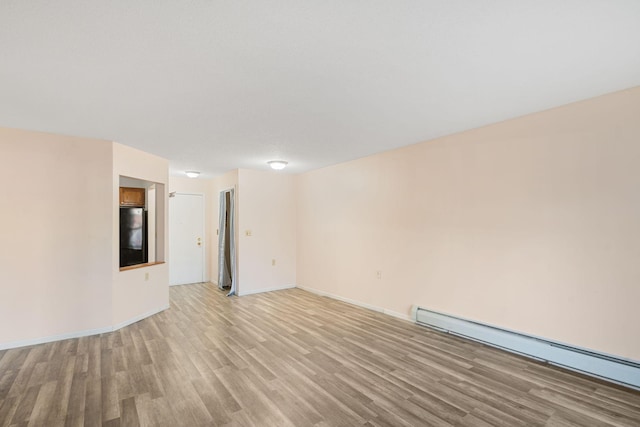 unfurnished room with light hardwood / wood-style floors and a baseboard heating unit