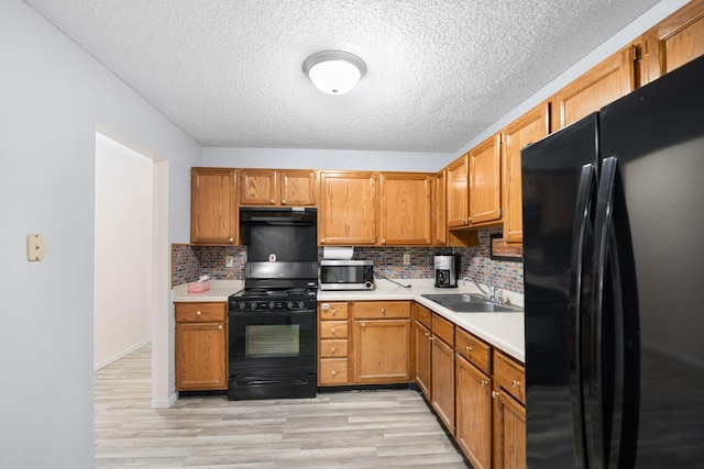 kitchen with sink, light hardwood / wood-style flooring, backsplash, a textured ceiling, and black appliances