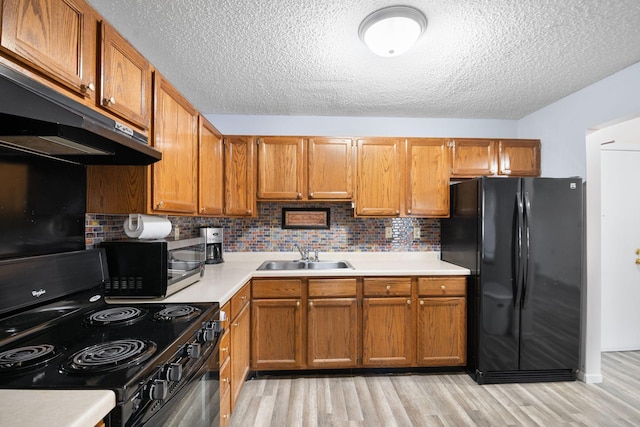 kitchen featuring decorative backsplash, sink, light hardwood / wood-style flooring, and black appliances